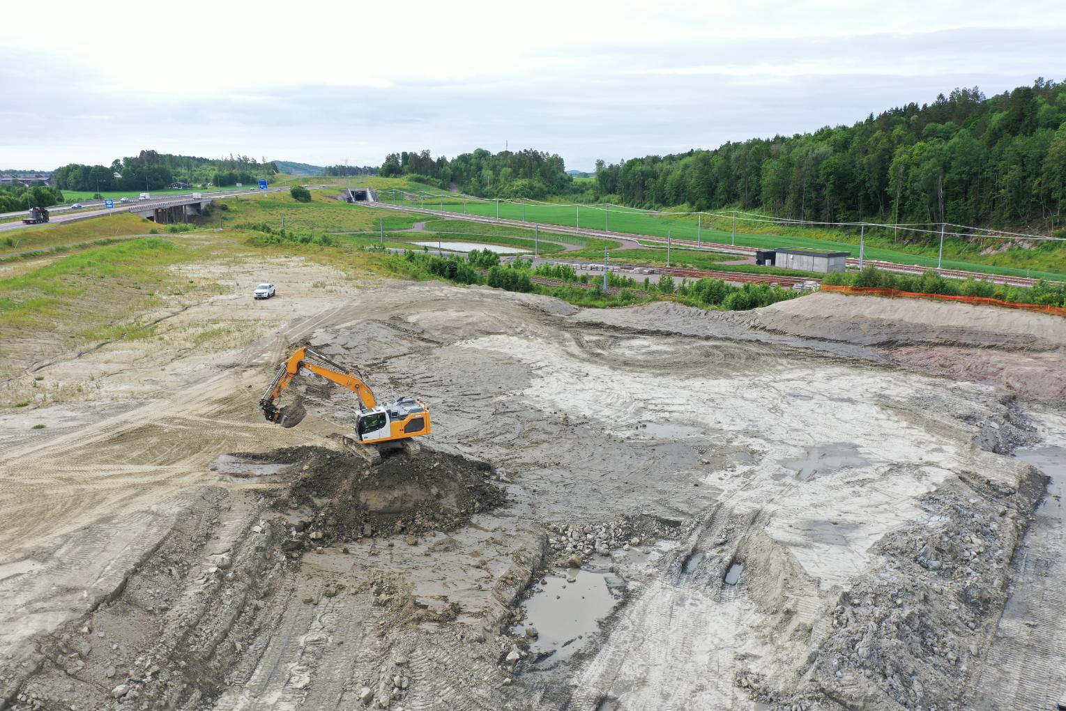 Gravemaskin utfører grunnarbeid ved jernbane og vei