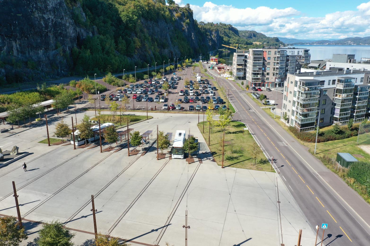 Dronebilde av parkeringsområde, boliger og vei langs fjorden