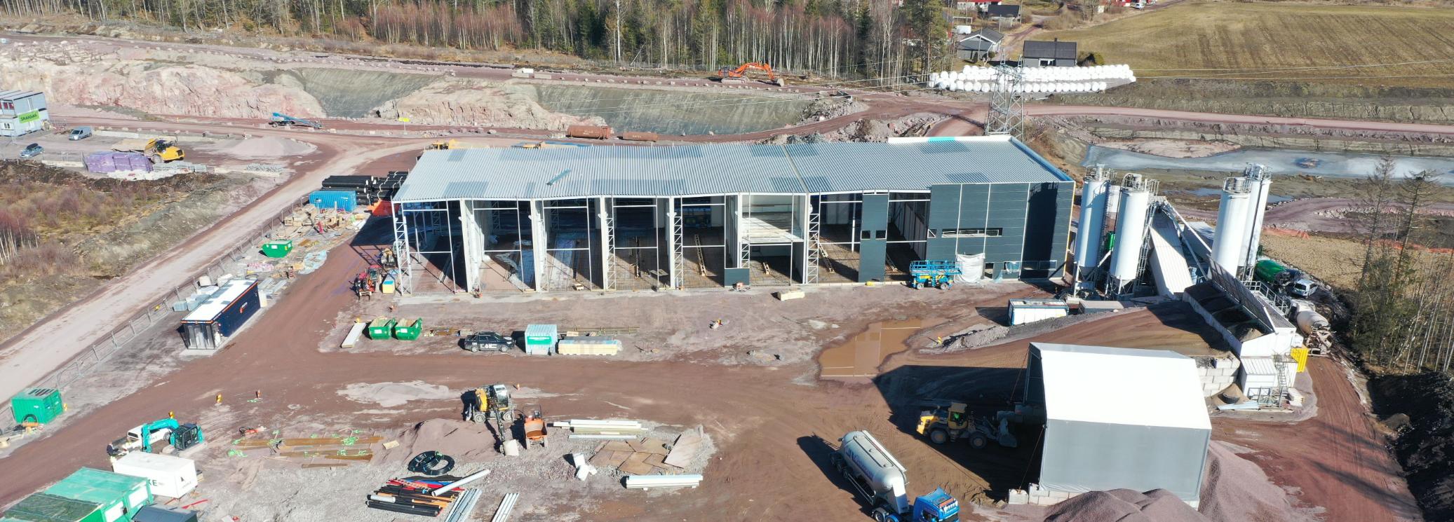 Dronebilde av industribygg under oppføring med siloer og anleggsmaskiner
